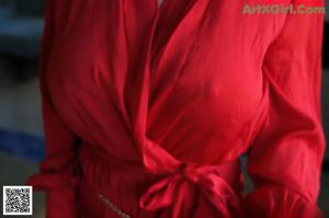 A woman in a red robe standing in a bathroom.