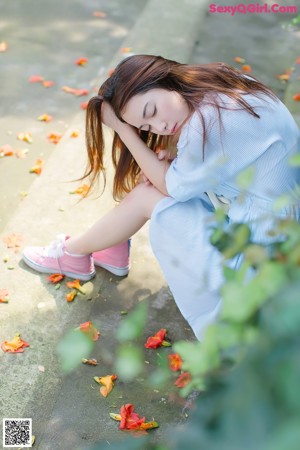 A woman sitting on the ground eating a slice of watermelon.