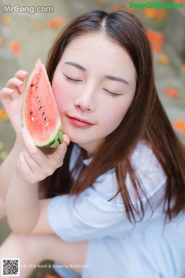 A woman holding a slice of watermelon in her hand.