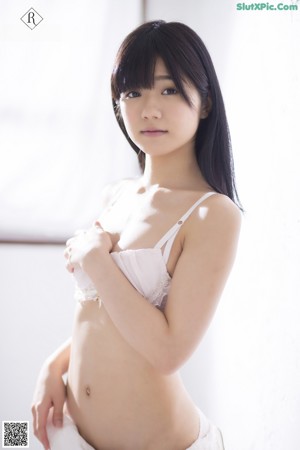A naked asian woman leaning against a white wall.