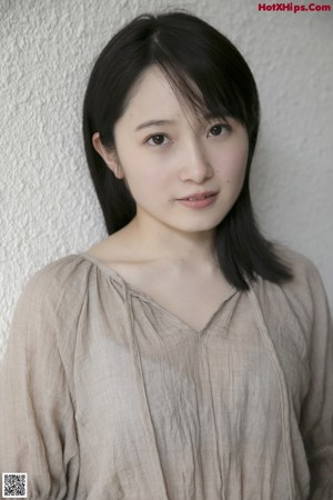 A woman in a beige dress sitting on a dirt road.