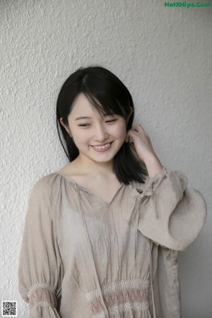 A woman leaning against a wall in a garden.