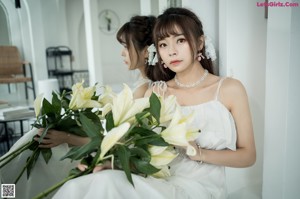 A woman in a white dress holding a bunch of flowers.