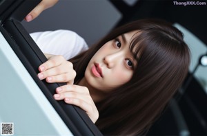 A woman in a school uniform sitting on a rock.