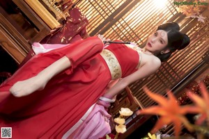 A woman in a red and gold outfit sitting on a table.