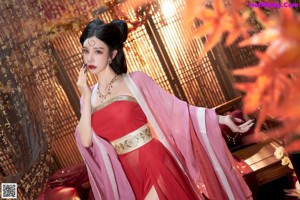 A woman in a pink kimono sitting on a chair.