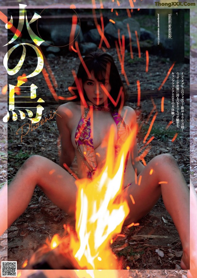 A woman in a bikini sitting next to a fire.