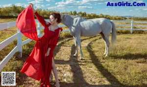 A woman in a black corset standing next to a white horse.