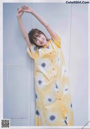 A woman in a yellow shirt is posing for a magazine.