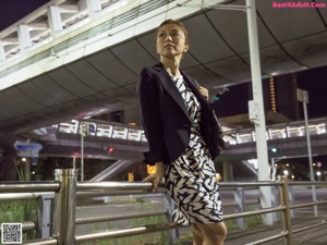 A woman walking down a sidewalk with a handbag.