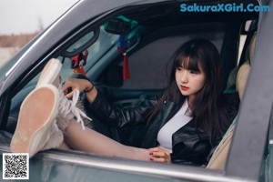 A woman sitting on top of a green car.