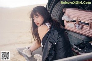A woman sitting on top of a green car.