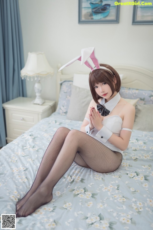 A woman in a bunny costume sitting on a bed.