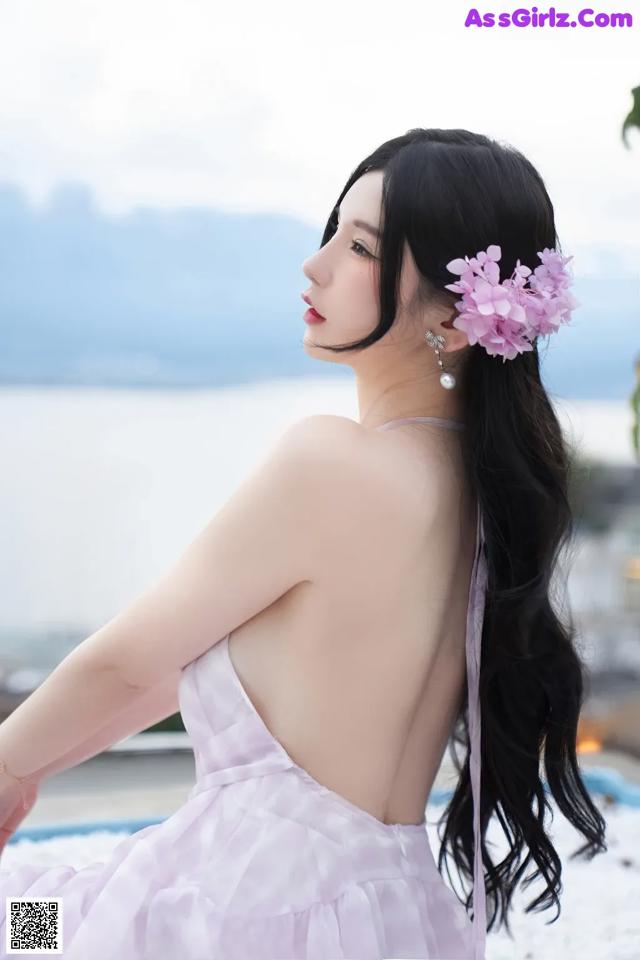 A woman in a pink dress with a flower in her hair.