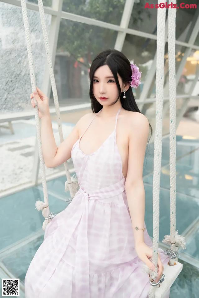 A woman in a pink dress sitting on a swing.