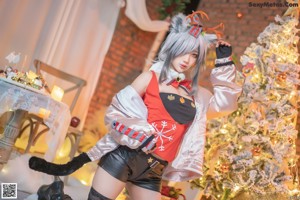 A woman sitting on a chair in front of a Christmas tree.