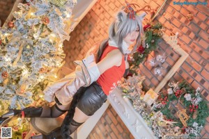 A woman in a red and white outfit posing in front of a Christmas tree.