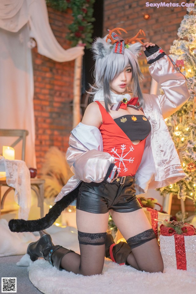 A woman in a red and white outfit posing in front of a Christmas tree.