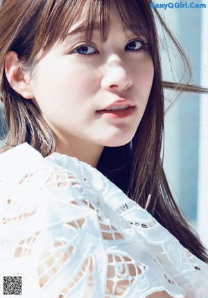 A woman in a white dress and black sandals posing for a magazine.