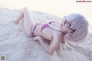 A woman in a purple bikini sitting on the beach.