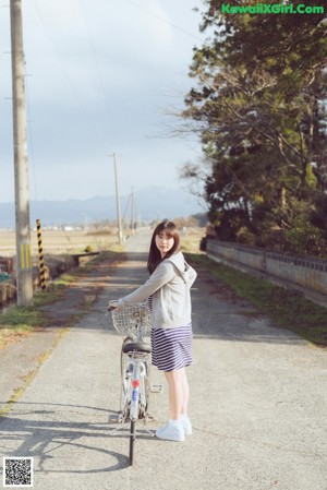 A woman riding a bike with a hoodie on.