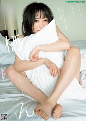 A woman sitting on a bed holding a pillow.