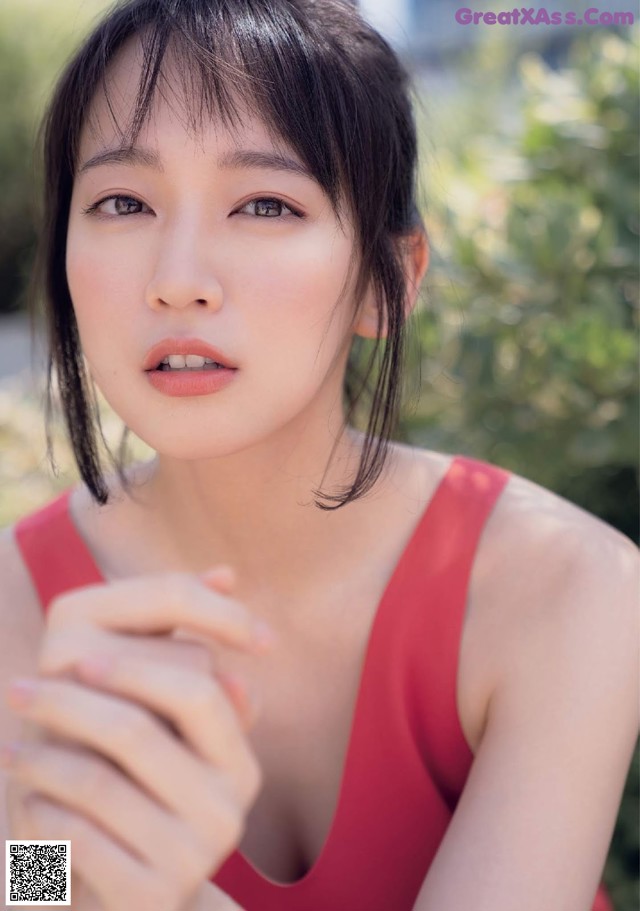 A woman in a red tank top posing for a picture.