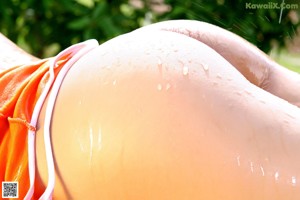 A woman in an orange top and blue shorts posing for a picture.