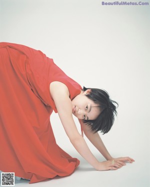 A woman in a red dress laying on the ground.